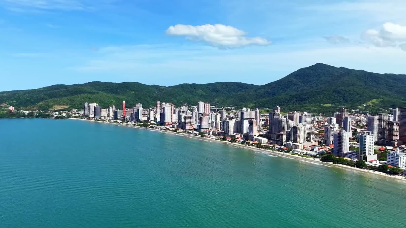 Vista aérea da orla verticalizada do litoral catarinense, com o morro ao fundo